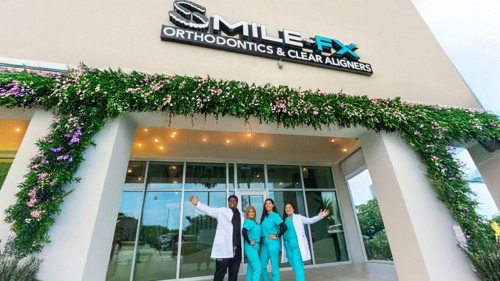 People standing at the entrance beneath the SMILE-FX® orthodontics and clear aligners sign.